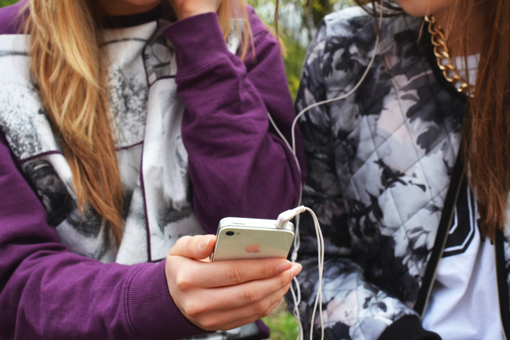 Two young women listening to music on an iPhone together